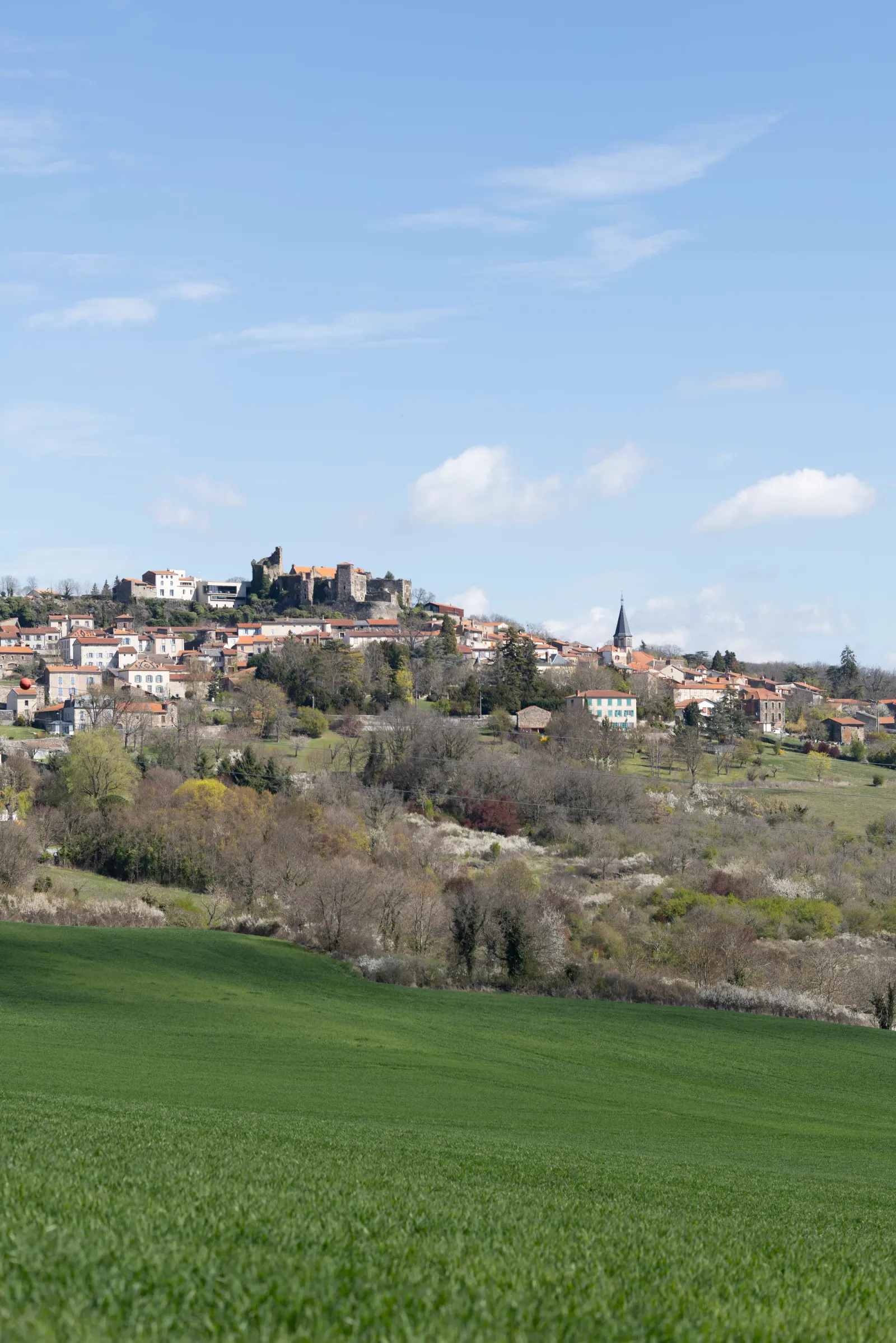 Perched village with a ruined castle and a church, surrounded by greenery and hills