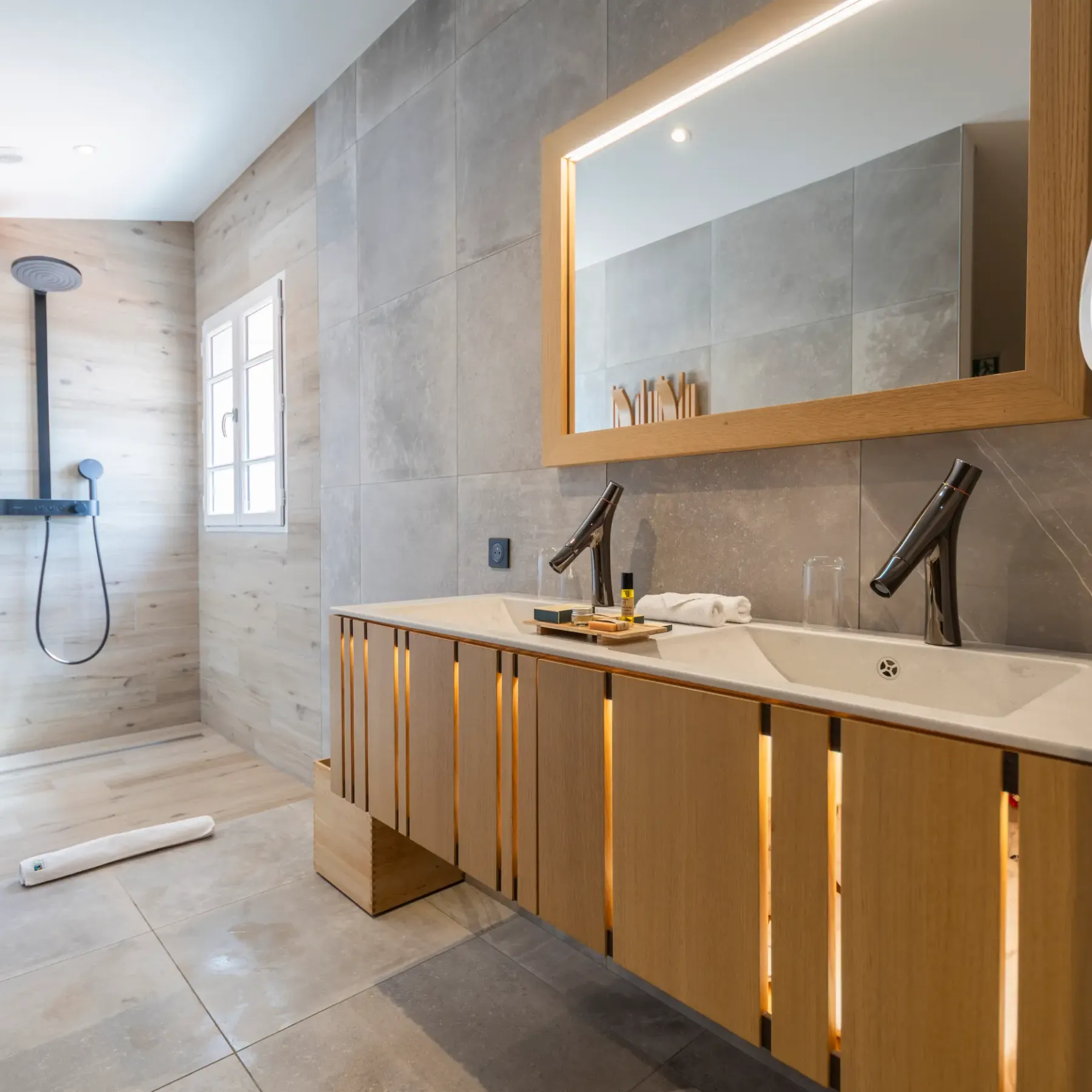 Modern bathroom with rain shower, double sink, and illuminated mirror
