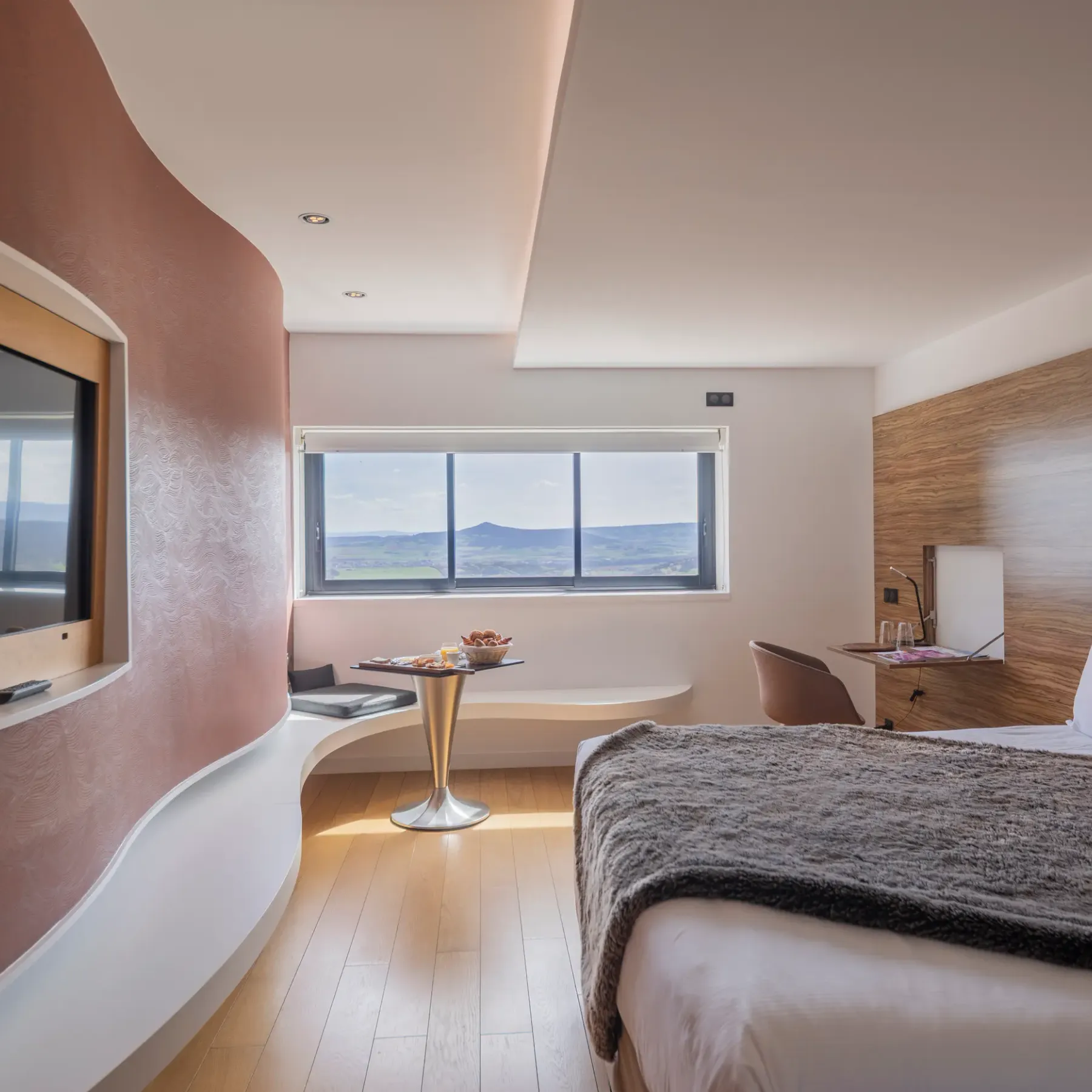 Modern room with bed, TV, table with fruit and panoramic view of the outdoor landscape