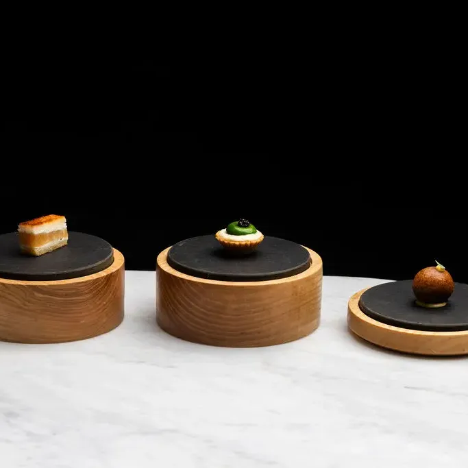 Three small wooden dishes with different foods on a marble worktop