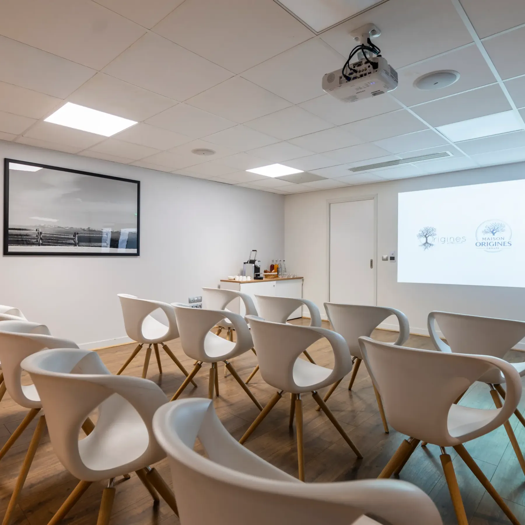 Meeting room with chairs arranged in a circle, a projector, and a screen displaying logos