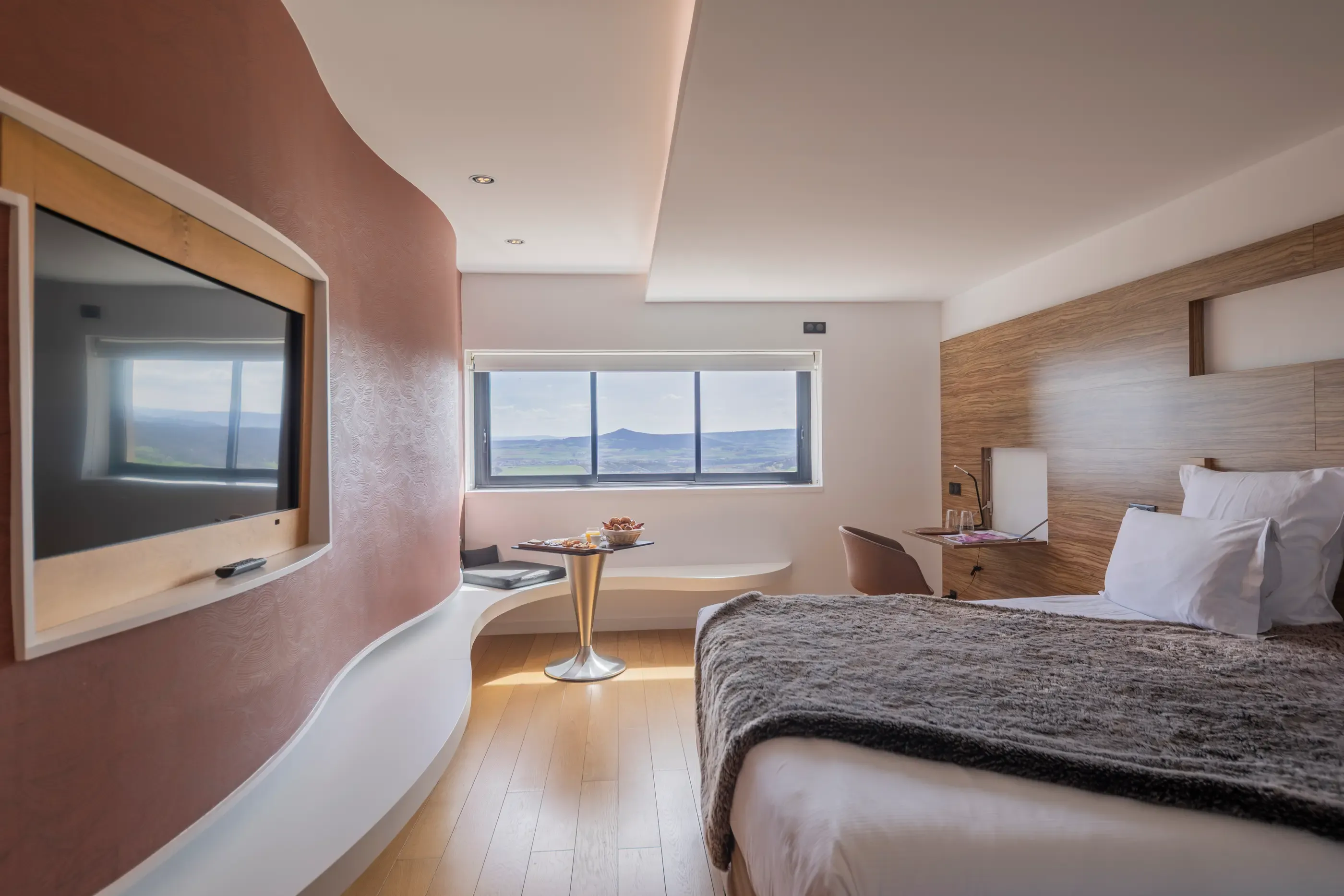 Modern room with bed, TV, table with fruit and panoramic view of the outdoor landscape