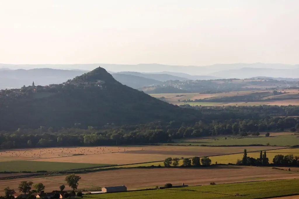 Paysage rural avec une colline boisée en arrière-plan et des champs cultivés en premier plan